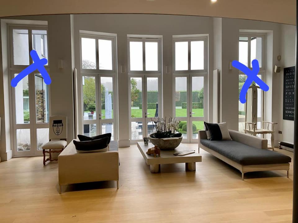 Living room with multiple windows, sofa, chair, coffee table, and open view of backyard.