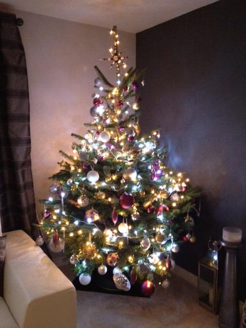 Christmas tree with colorful lights and ornaments in a living room.