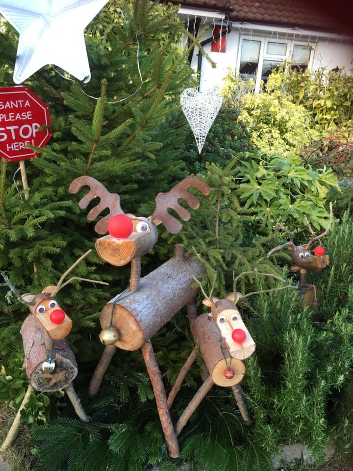 Christmas yard decorations: wooden reindeer with red noses and antlers, a star, and a Santa stop sign.