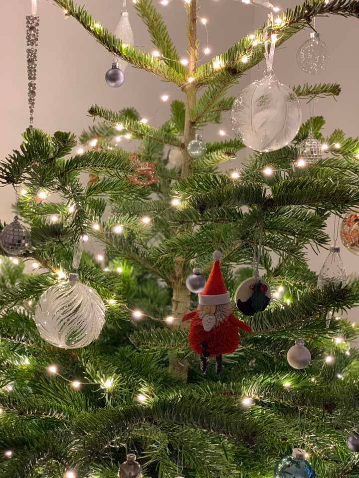 Christmas tree decorated with ornaments and lights. Santa Claus ornament is visible.
