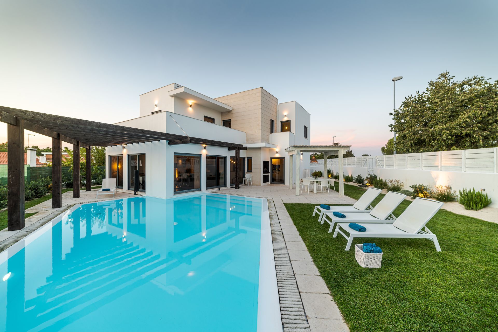 A modern house with a garden, a swimming pool, and a wooden pergola. A modern house with a garden, a swimming pool, and a wooden pergola.