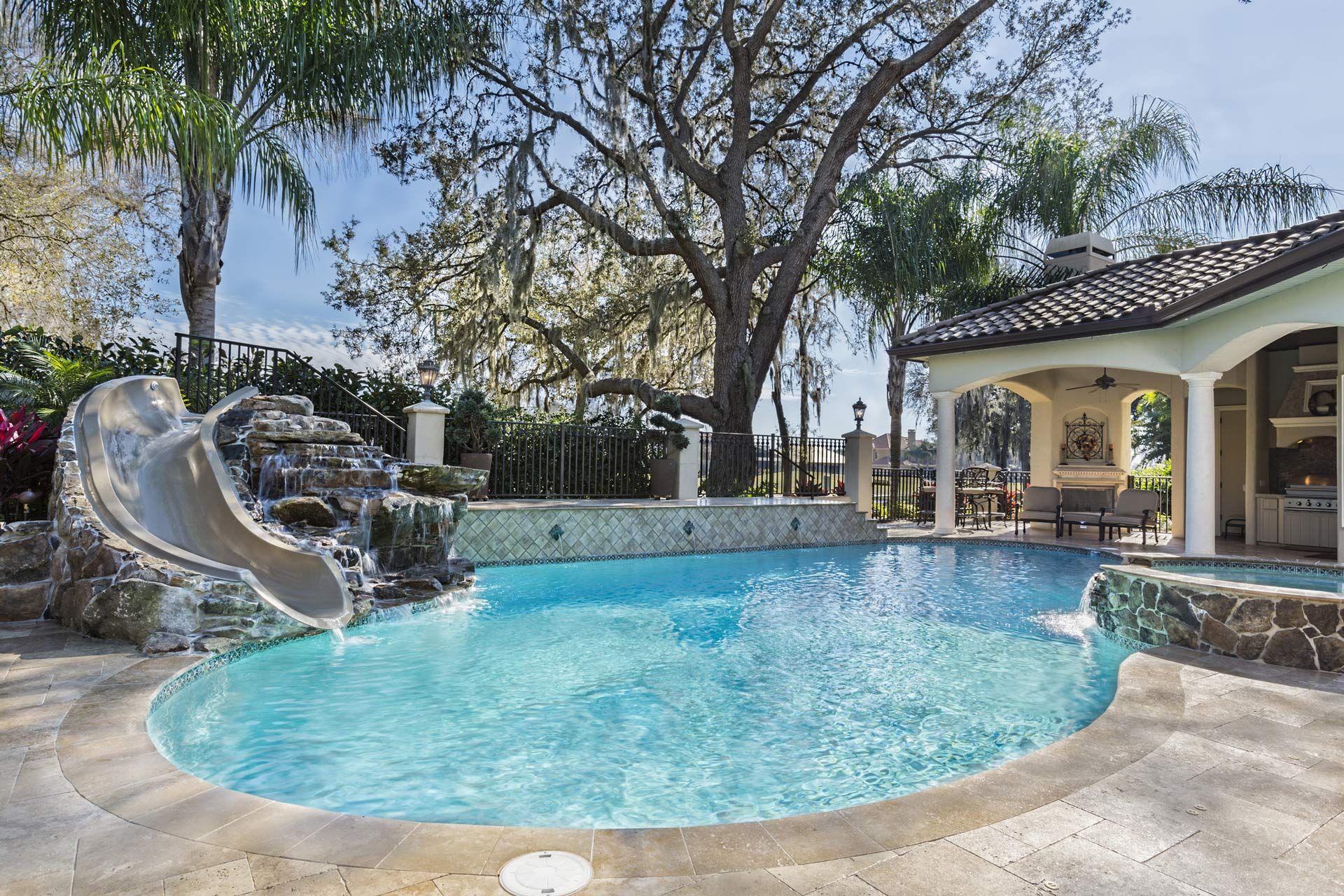 A swimming pool with a slide, spa, and waterfall, showcasing expert pool renovation services.