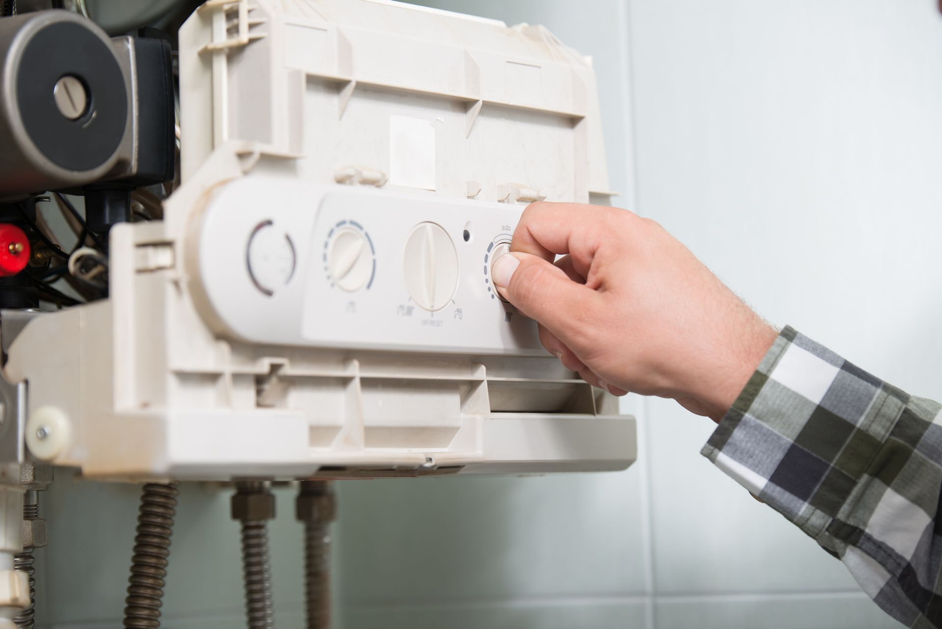 A person is adjusting a boiler in a bathroom.