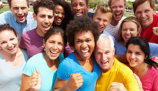 Group of diverse people smiling and cheering outdoors.