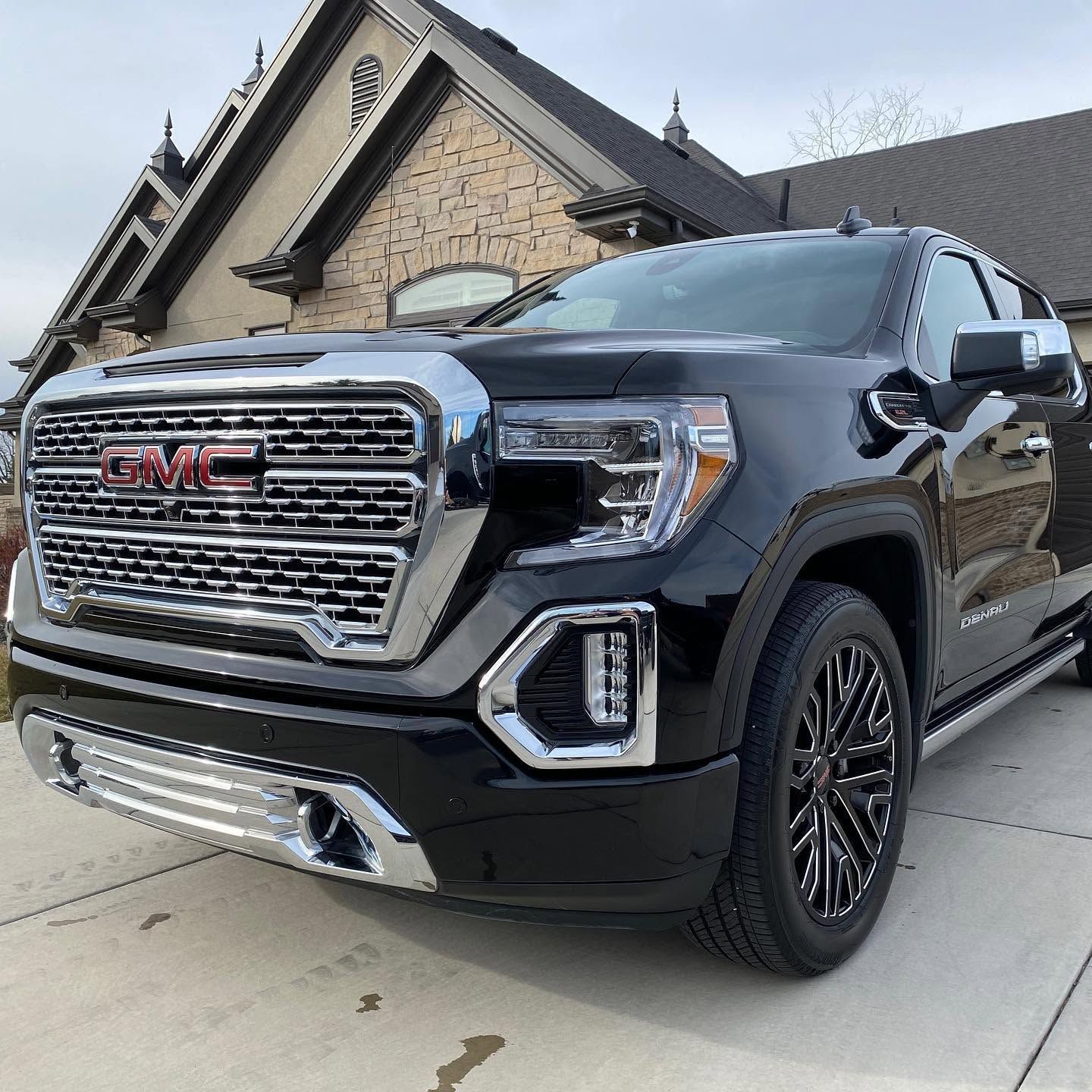 Black GMC pickup parked in a driveway in front of a house