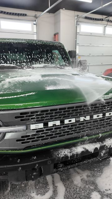 A car is being washed with foam in a garage.