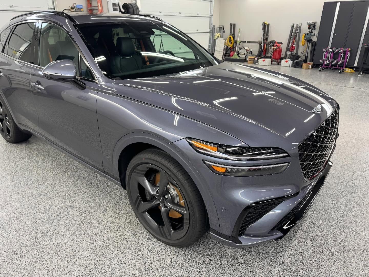 Gray SUV in an auto shop, front-left view, with black wheels and orange brake calipers