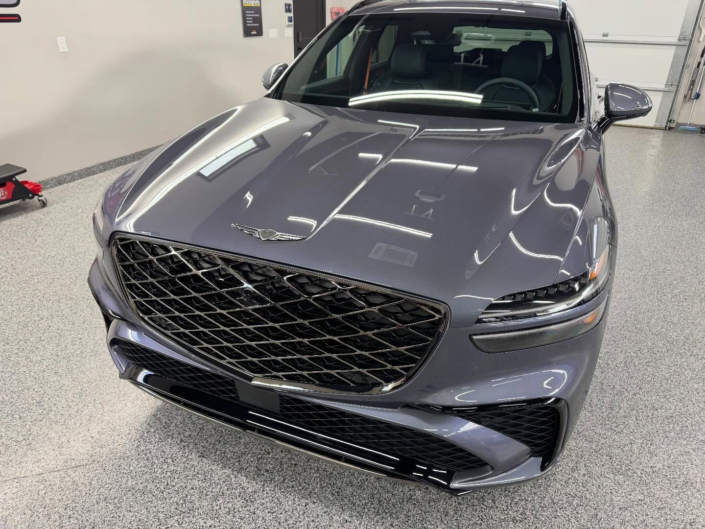 Gray Genesis sedan in a garage, front view with large grille and sleek headlights