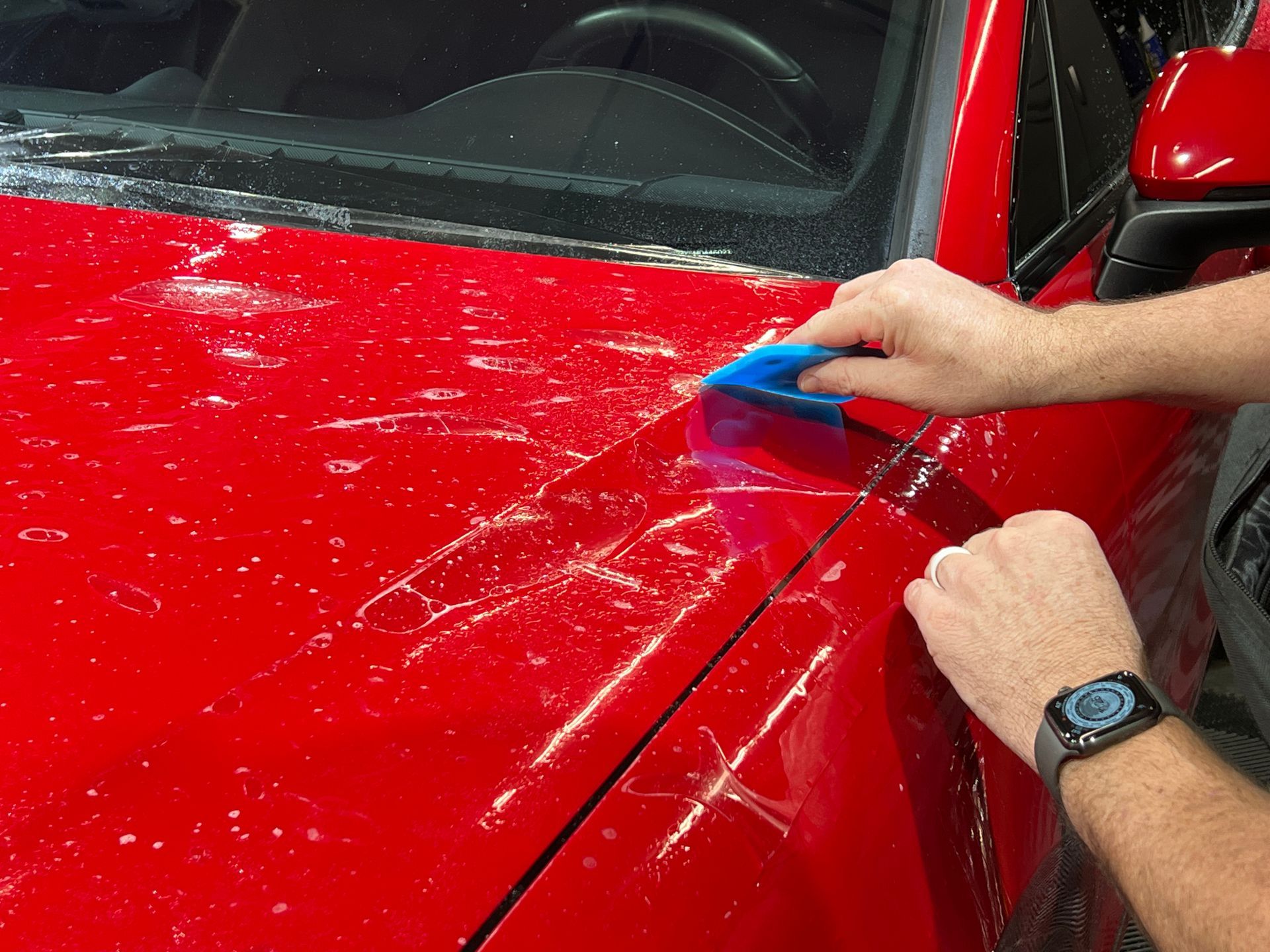 Technician applying a protective film to the hood