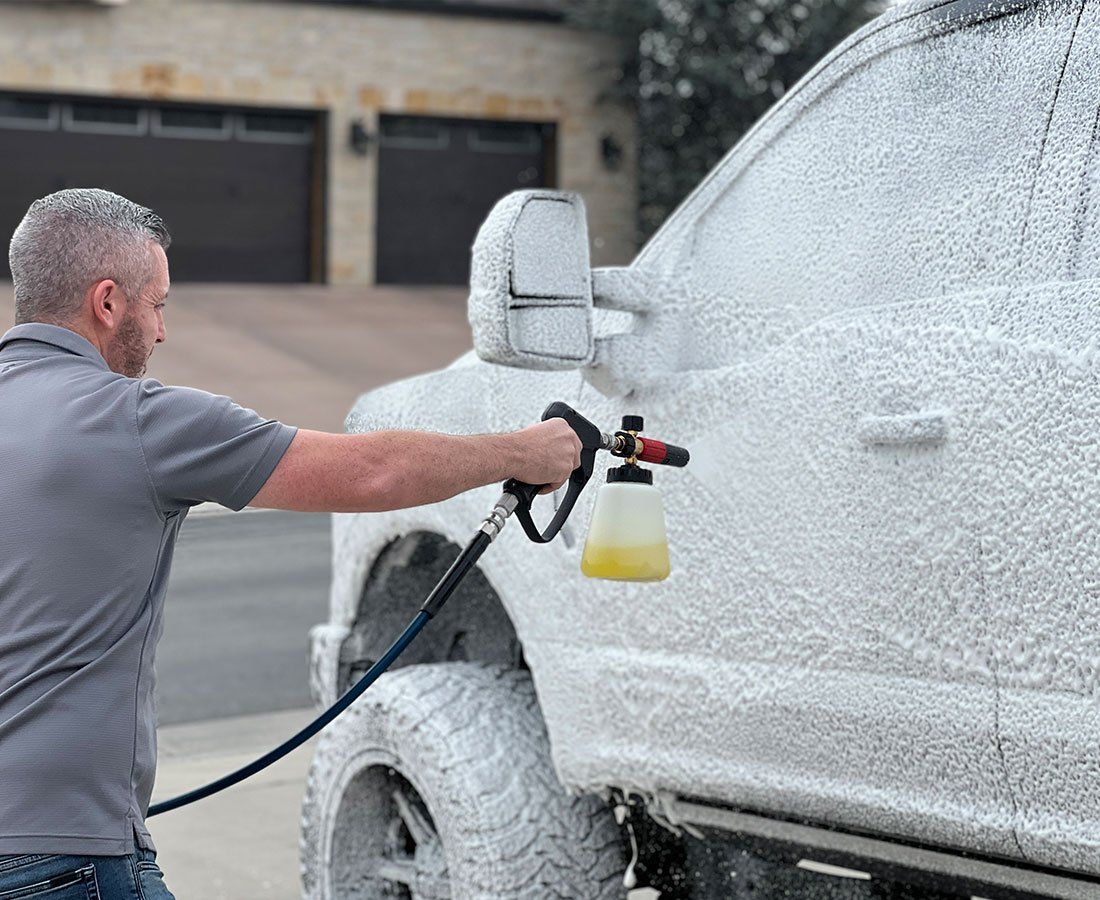 A man is spraying foam on a white truck.