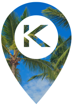 A map pin icon with a white background and the letter "K" in the center, overlaid on a blue sky with palm tree leaves.