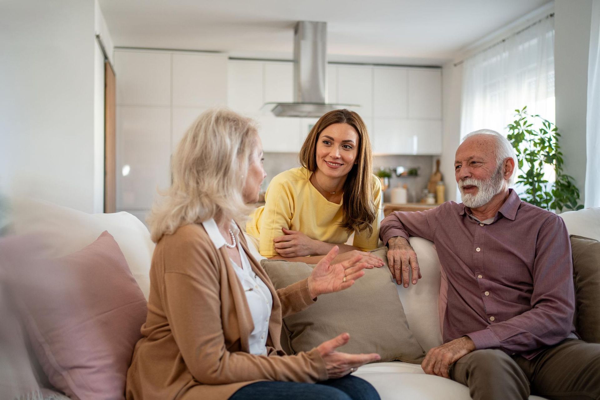 Three people chatting on a couch in a bright living room