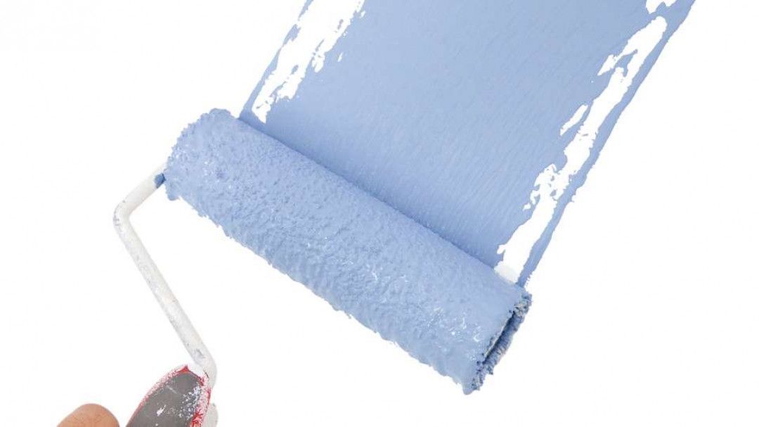 A person is painting a wall with a blue paint roller.