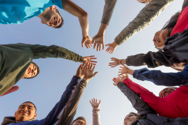 A group of people are standing in a circle with their hands in the air.