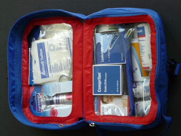 A blue and red first aid kit filled with various items