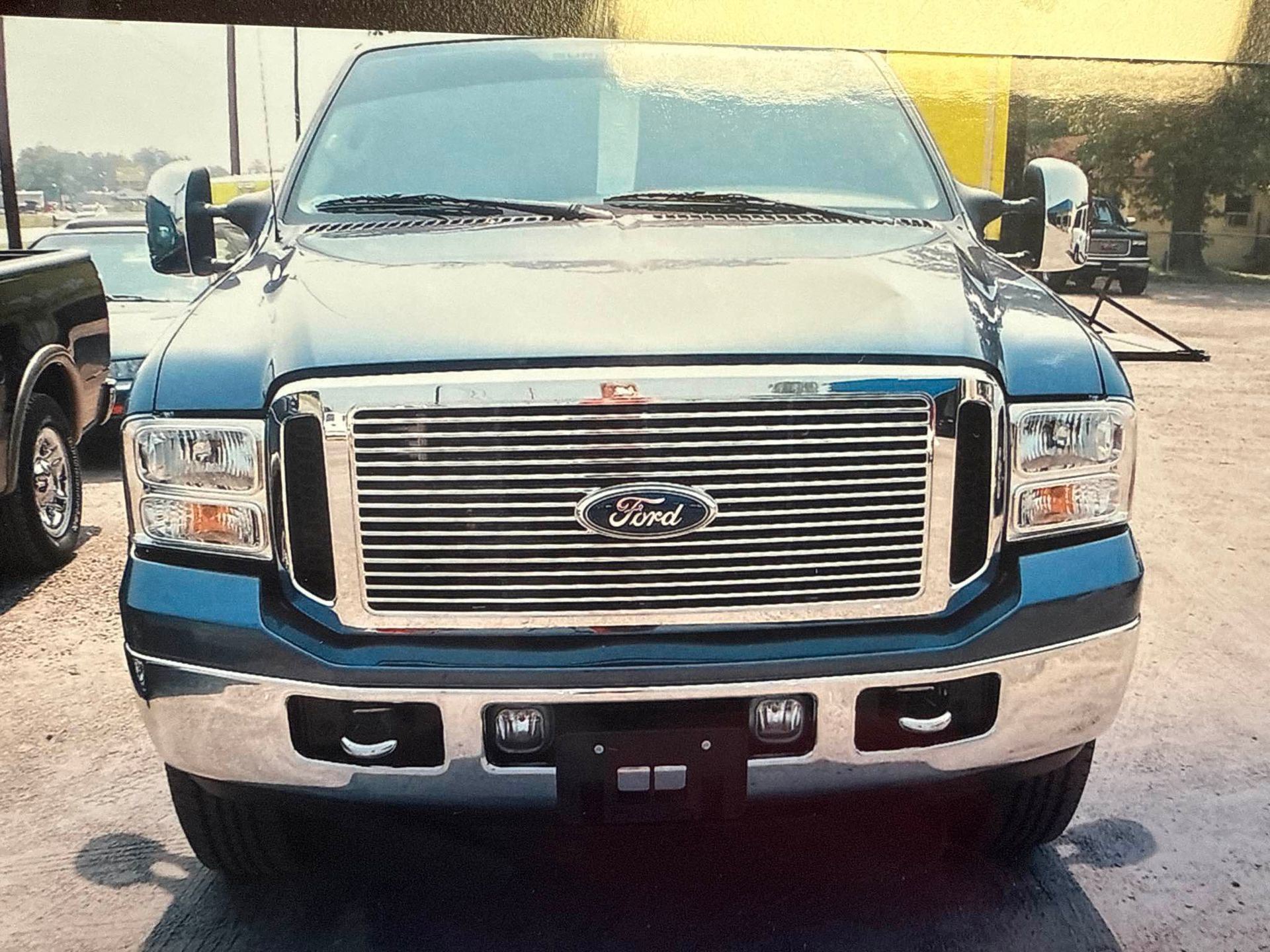 Damaged black Ford pickup truck front end with crushed bumper and grille in a garage