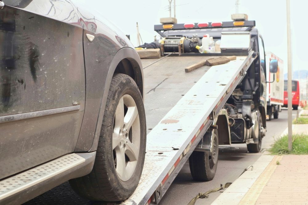 Black car being loaded onto a tow truck on a city street.