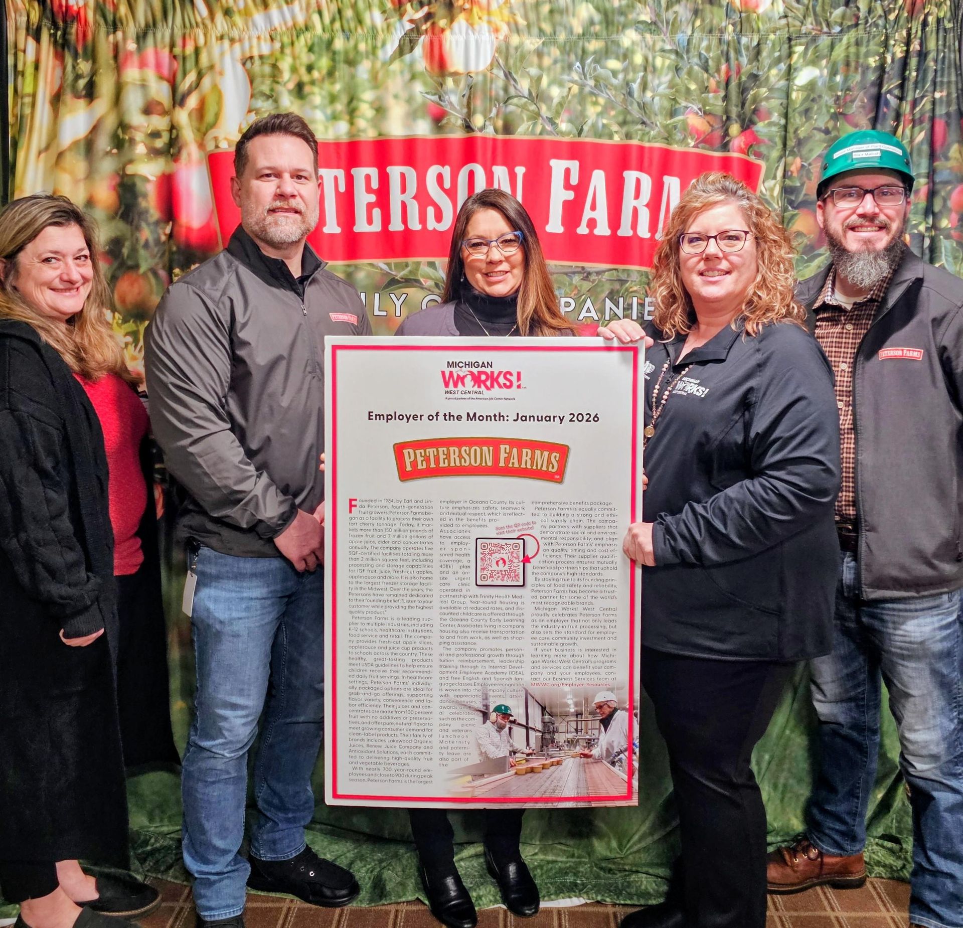 Five people holding a framed award poster in front of a red Patterson Farms sign outdoors