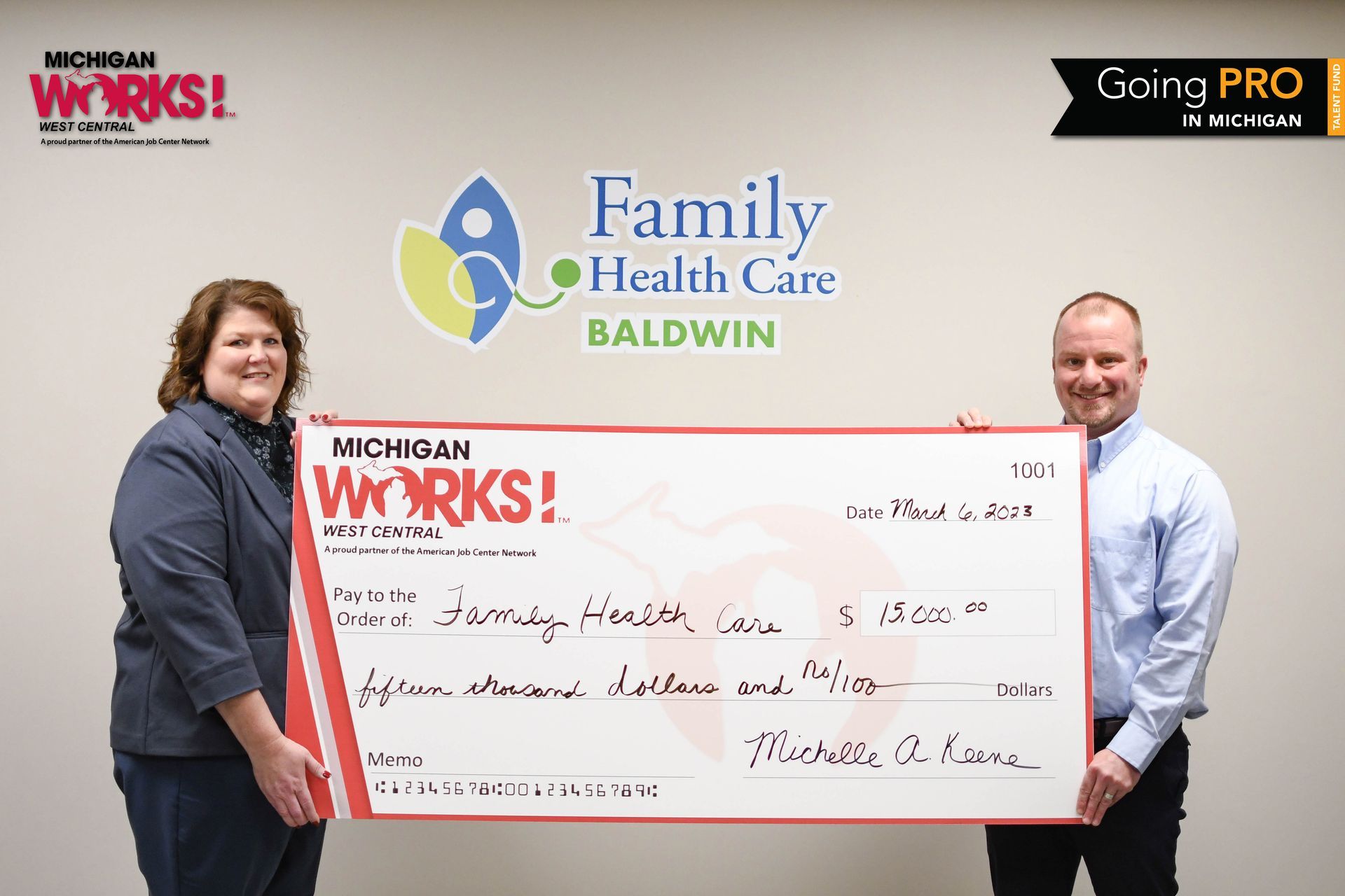 Michigan Works! West Central Executive Director Shelly Keene presents Alan Neushwander, director of external and internal relations for Family Health Care, with a check after the organization completed its FY22 Going PRO Talent Fund training plan.