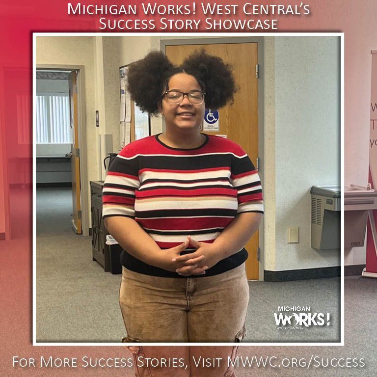 Woman standing in an office hallway with hands clasped, framed by a “Michigan Works!” success story backdrop