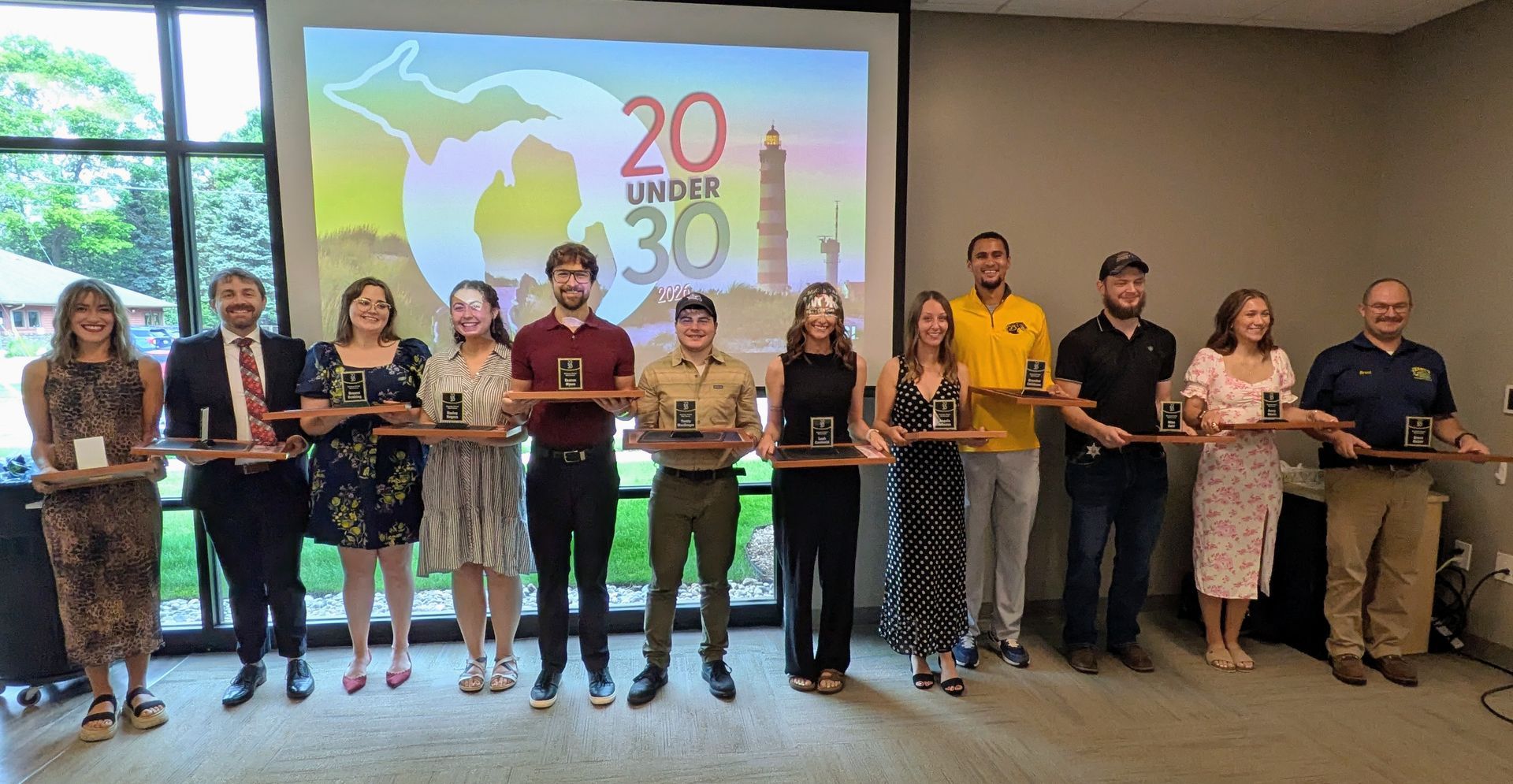 Group of people holding a long ribbon in a conference room with a “20 30” presentation slide behind them