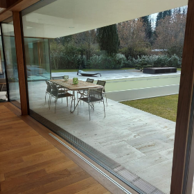 Blick durch ein Fenster auf eine Terrasse mit Tisch und Stühlen