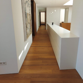 Ein langer Flur mit Holzboden und einer weißen Theke