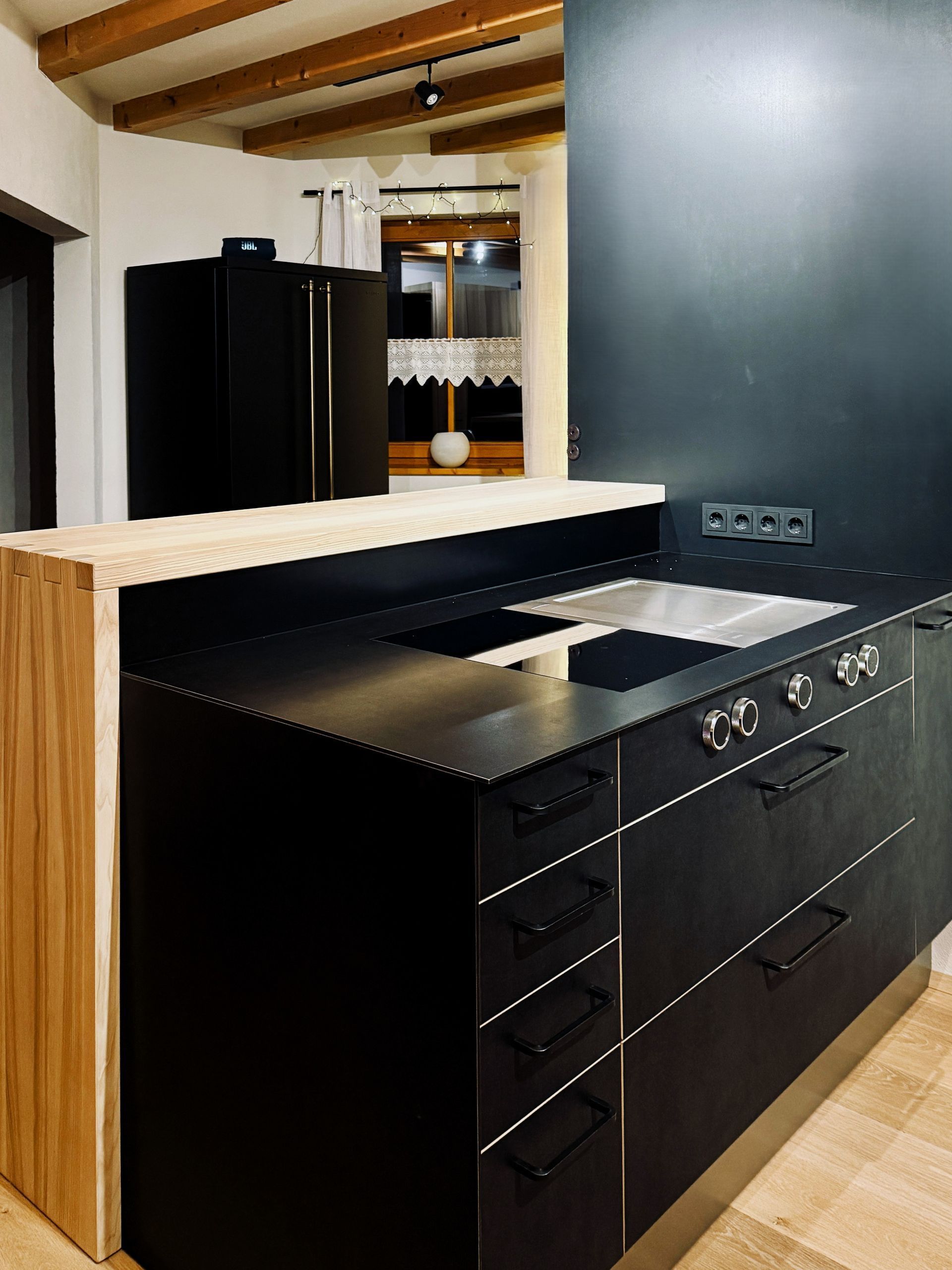 Moderne Kücheninsel mit schwarzen Schränken, Holzelementen und einer hellen Arbeitsplatte in einem zeitgenössischen Interieur