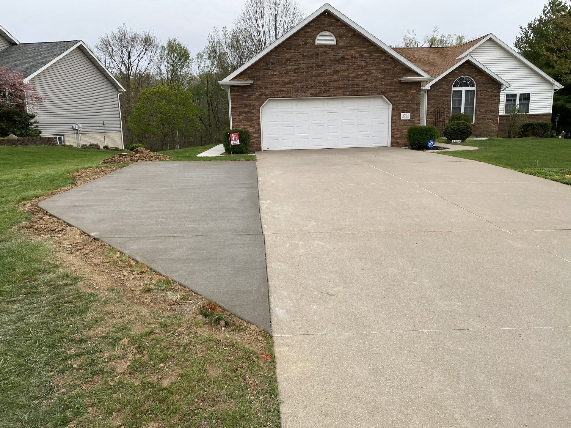 A brick house with a concrete driveway in front of it.