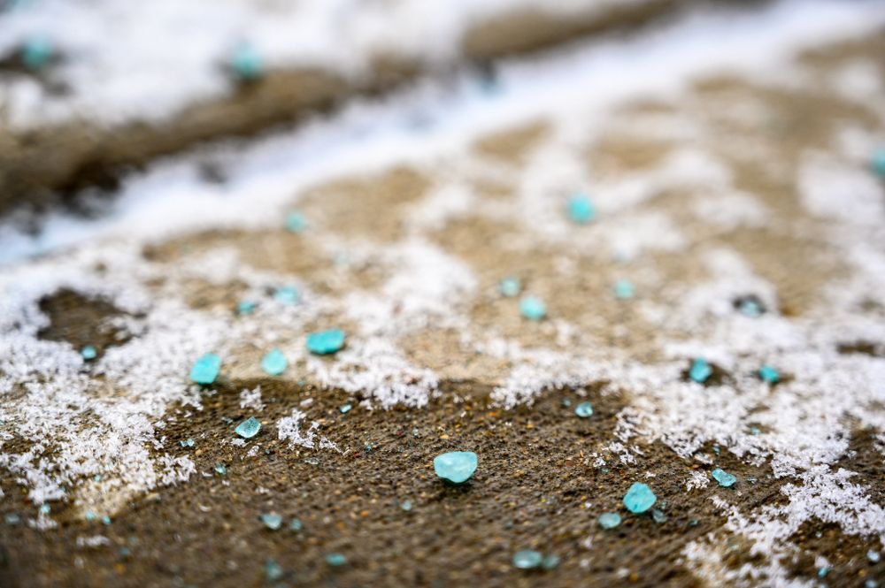 Turquoise crystals scattered on a dusty, snow-dusted ground outdoors