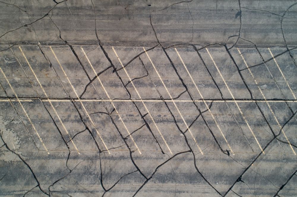 Cracked concrete surface with diagonal white painted lines and weathered markings
