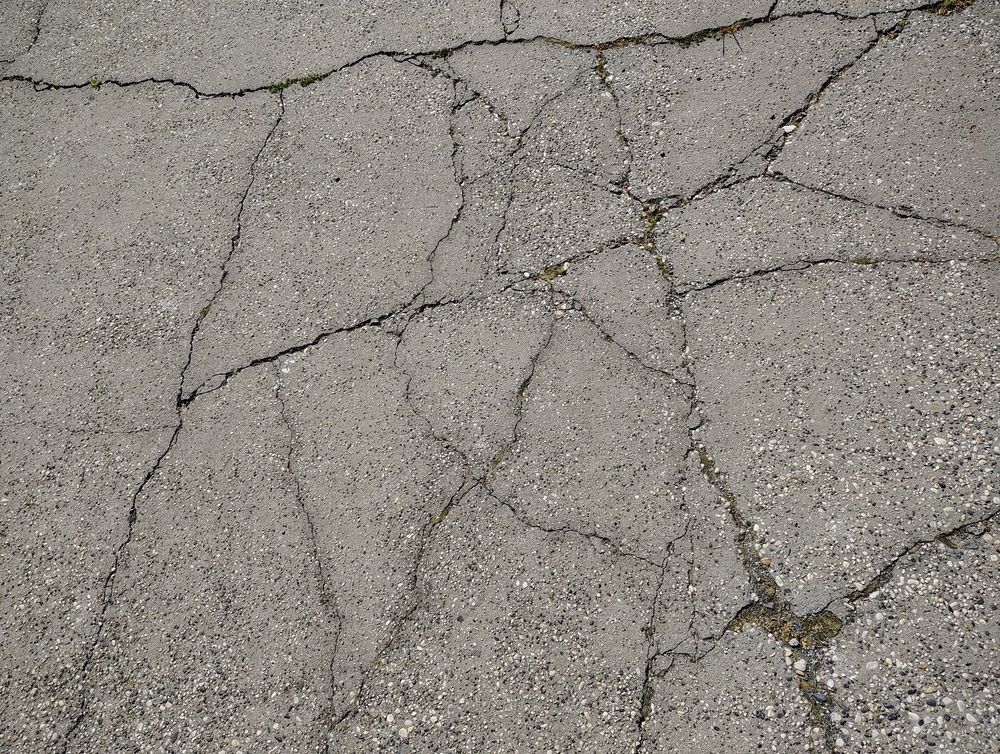 Cracked gray asphalt pavement with multiple intersecting fissures