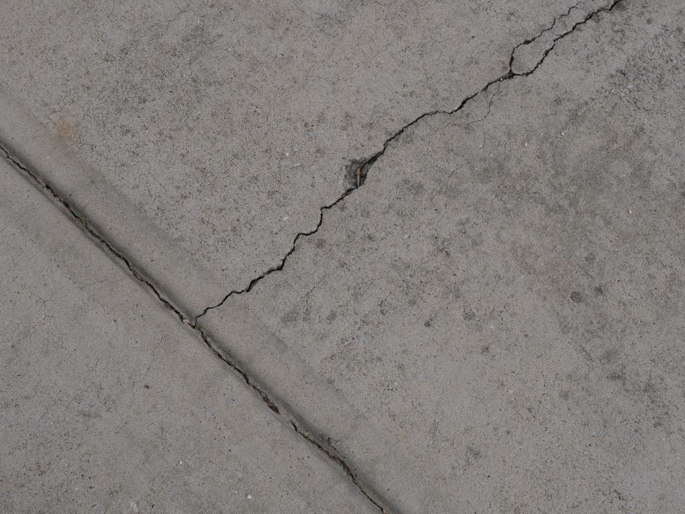 Cracked gray concrete pavement with a diagonal seam