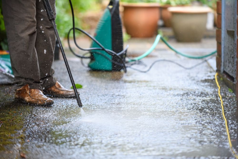 Cleaning a concrete patio with a pressure washer.