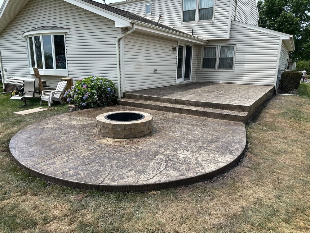 Backyard patio with raised fire pit and curved concrete seating area beside a house