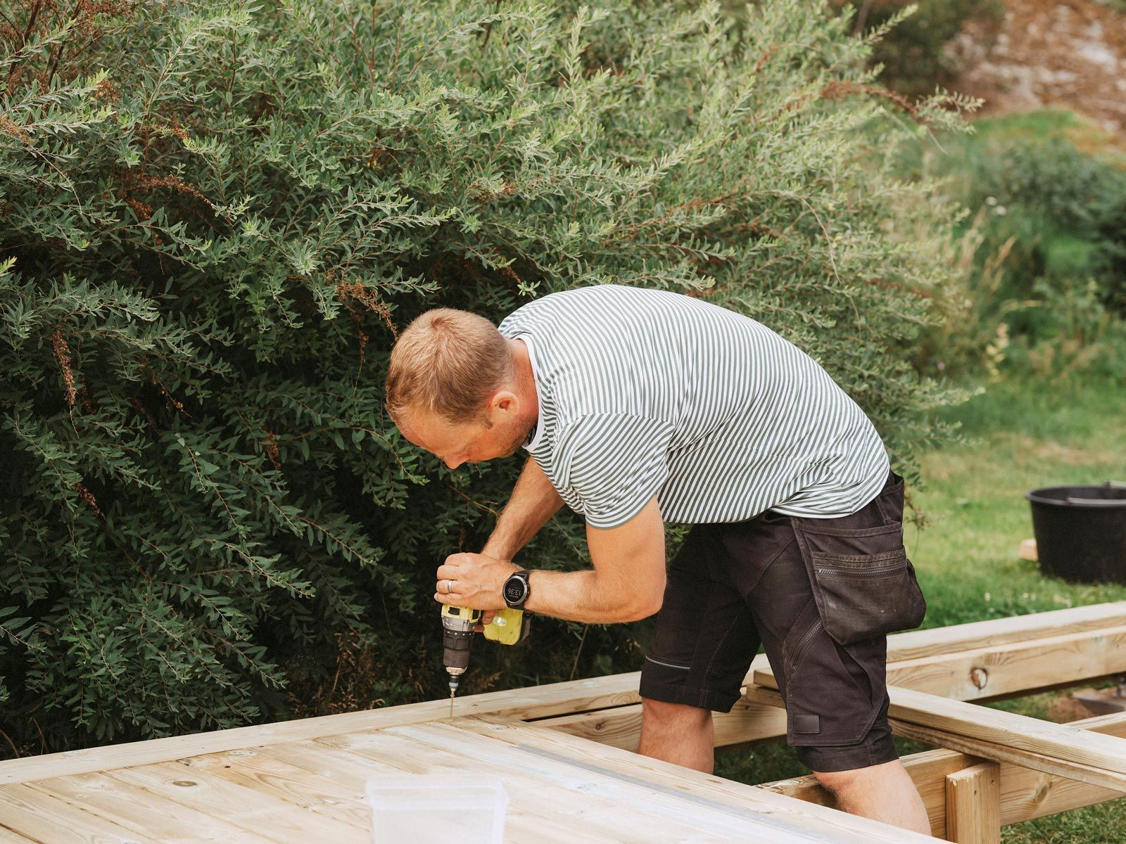 Man building a wooden deck outdoors for home improvement.