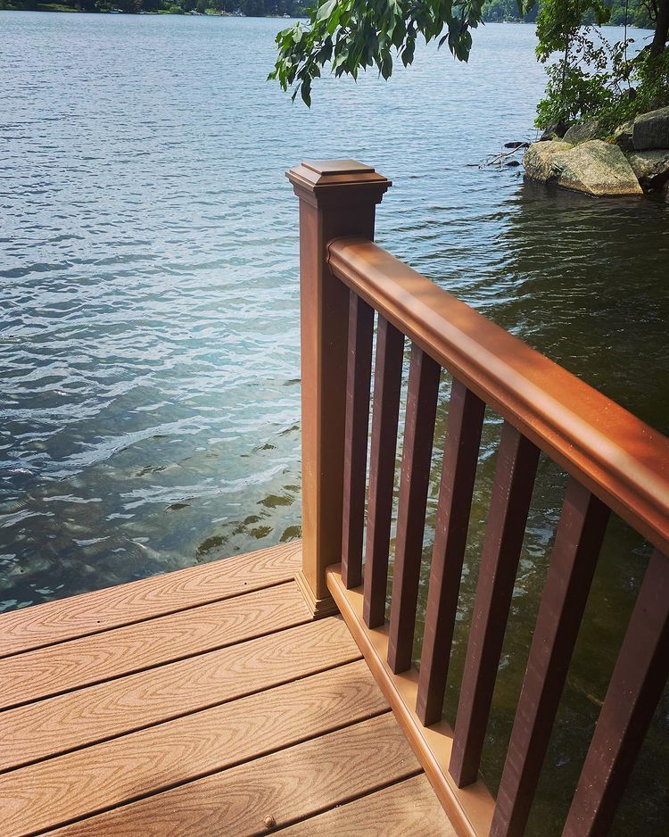 Wooden deck and railing overlooking a lake, with brown hues, and water ripples.