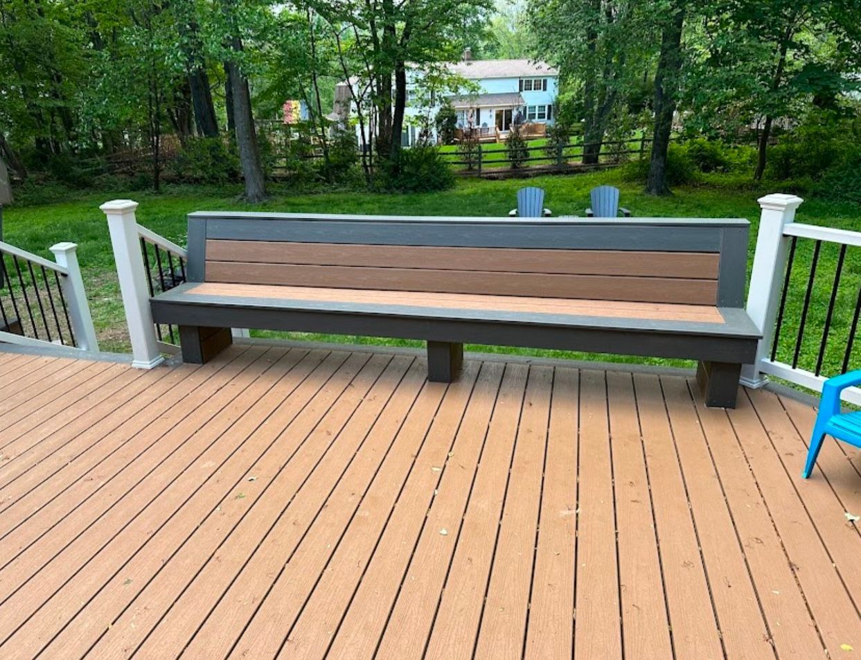 Large bench on a deck, brown and gray, with a house in the background.