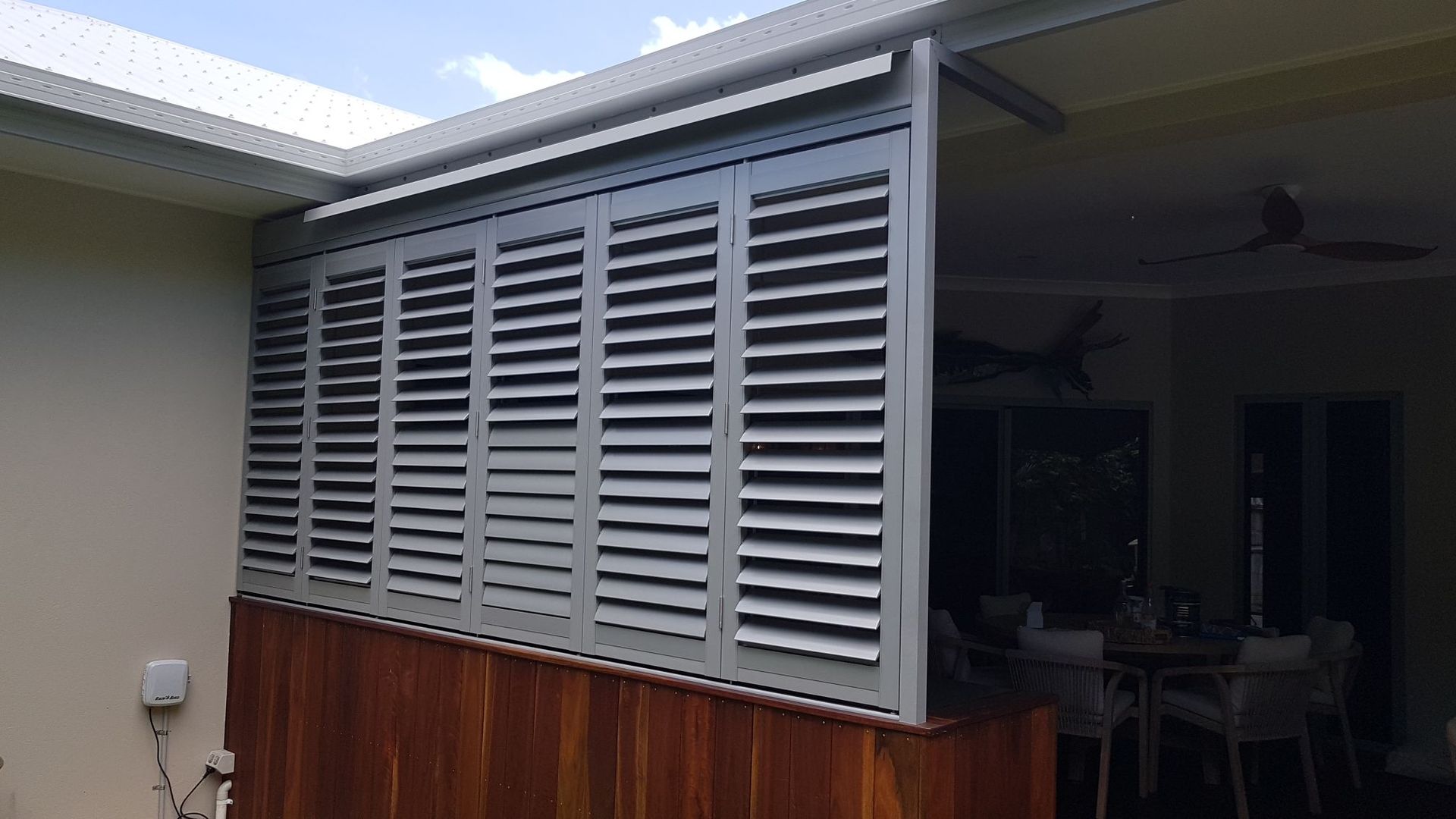 A Living Room with A Sliding Glass Door and White Louvres on The Windows — A & B Lattice World & Patios in Bungalow, QLD