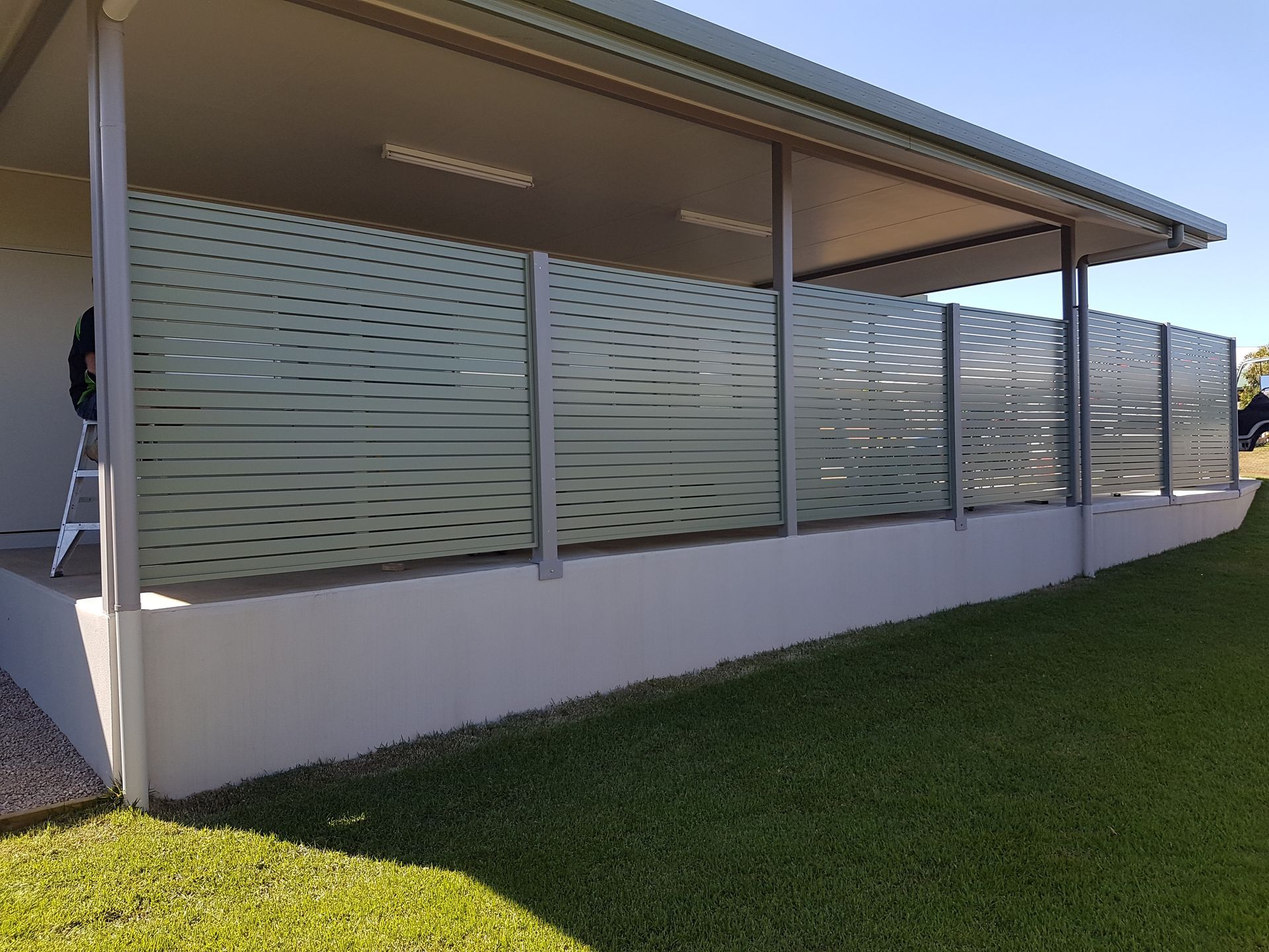 A House with A Metal Siding and A Garage with The Door Open — A & B Lattice World & Patios in Bungalow, QLD