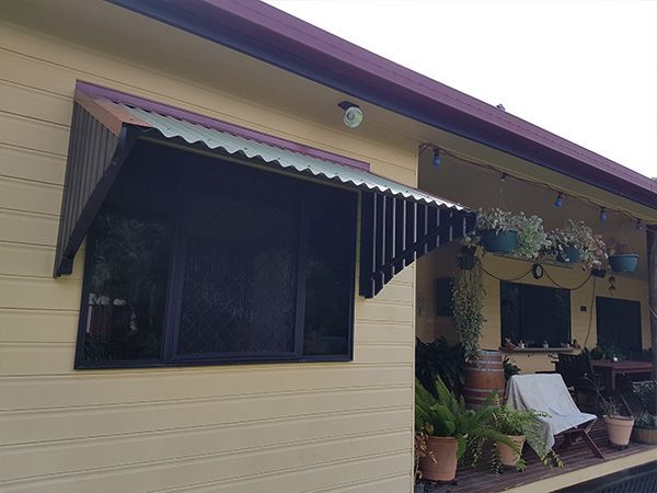 A House with A Screened in Window and A Porch with Chairs and Potted Plants — A & B Lattice World & Patios in Bungalow, QLD