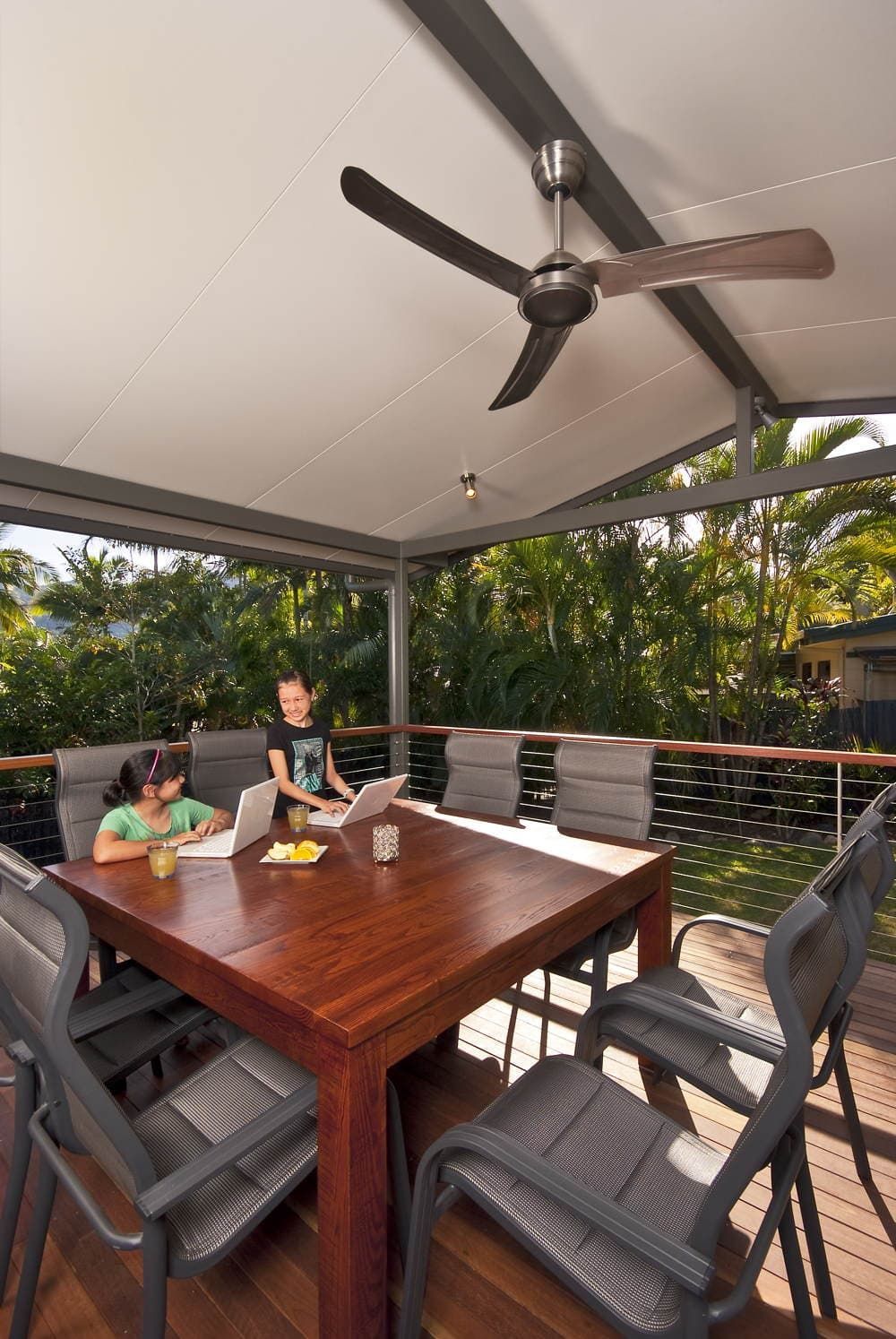 Two Children Are Sitting at A Table with A Laptop and A Ceiling Fan — A & B Lattice World & Patios in Bungalow, QLD