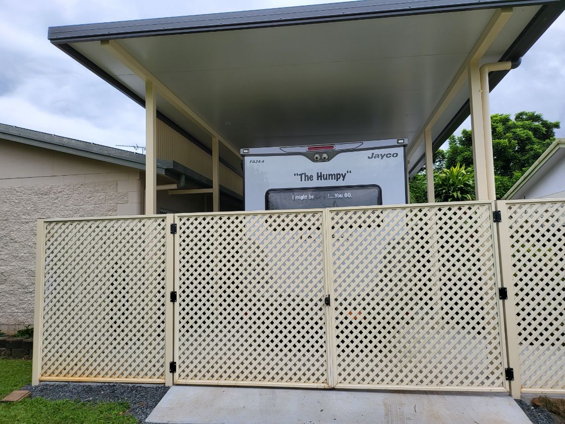 A White Gate Is Leading to A House Surrounded by Plants  — A & B Lattice World & Patios in Bungalow, QLD