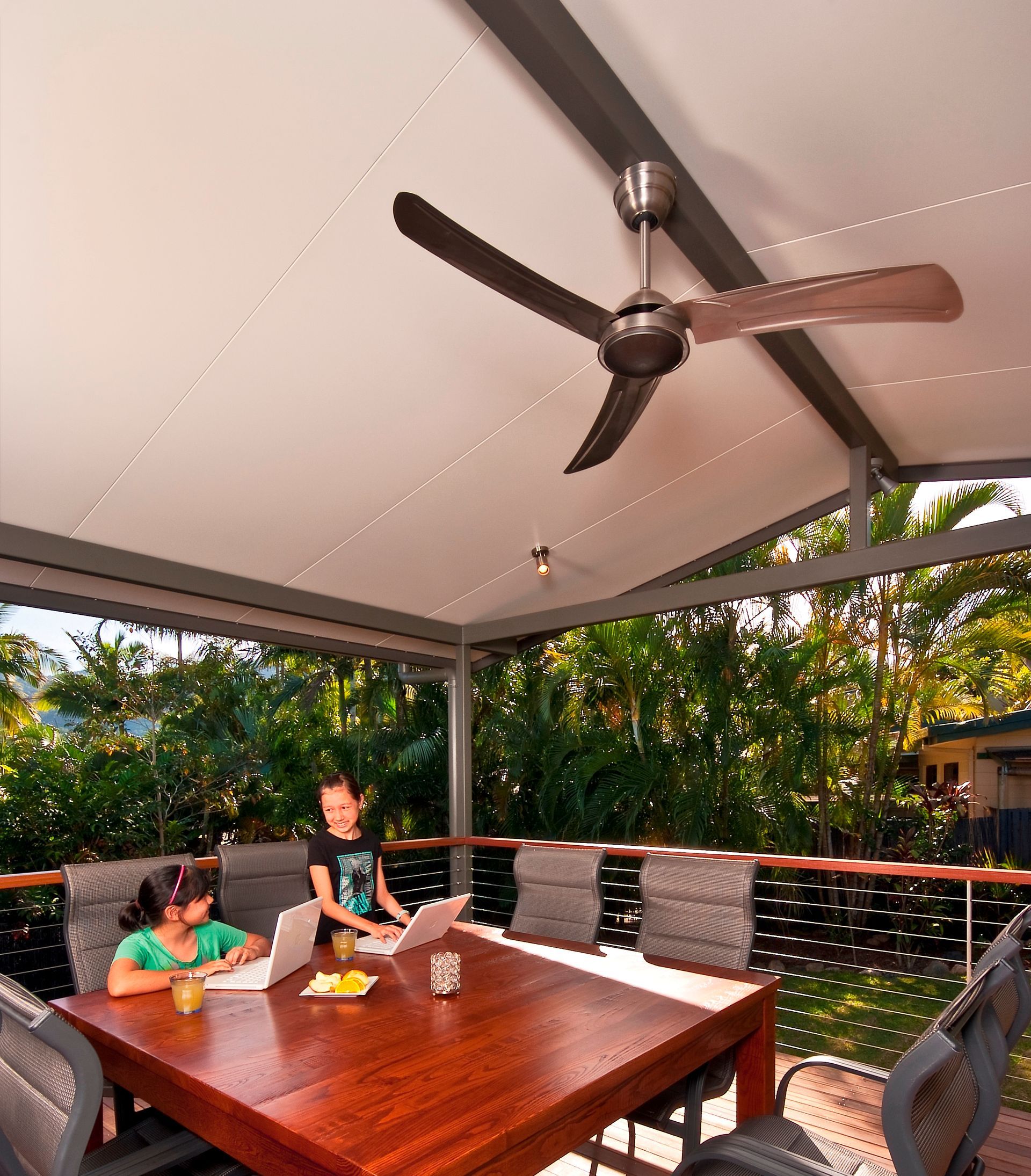 A Group of People Are Sitting at A Table with A Laptop and A Ceiling Fan — A & B Lattice World & Patios in Bungalow, QLD