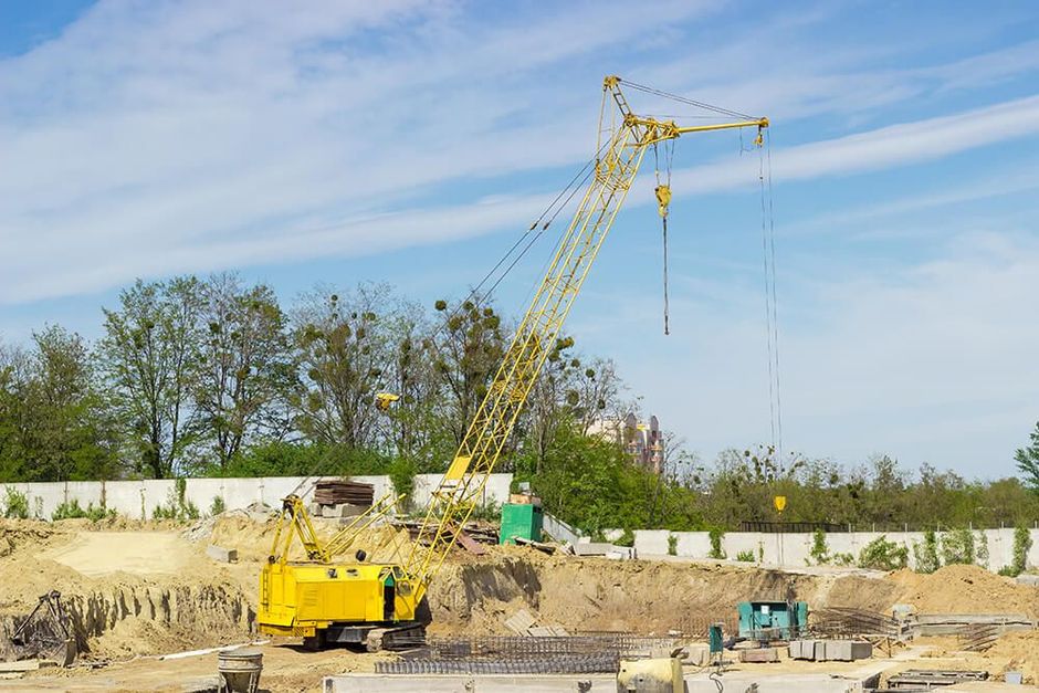 a yellow crane sitting on top of a pile of dirt