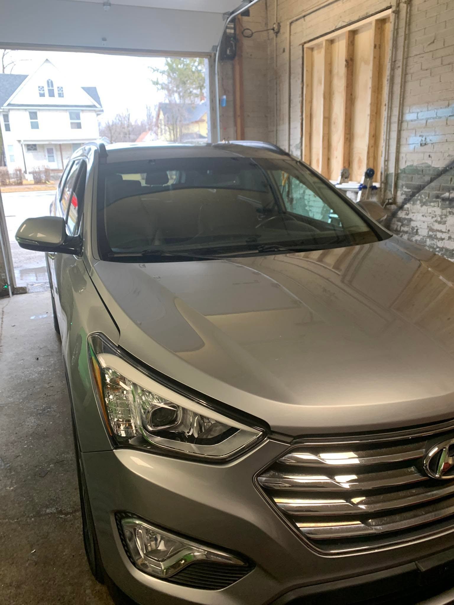 Silver SUV parked in a garage, front view with headlights and grille visible