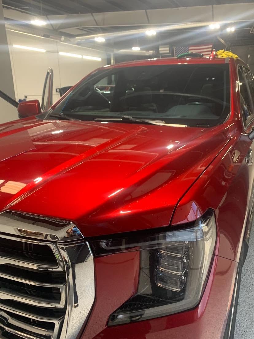 Red pickup truck with a glossy hood parked inside a garage.