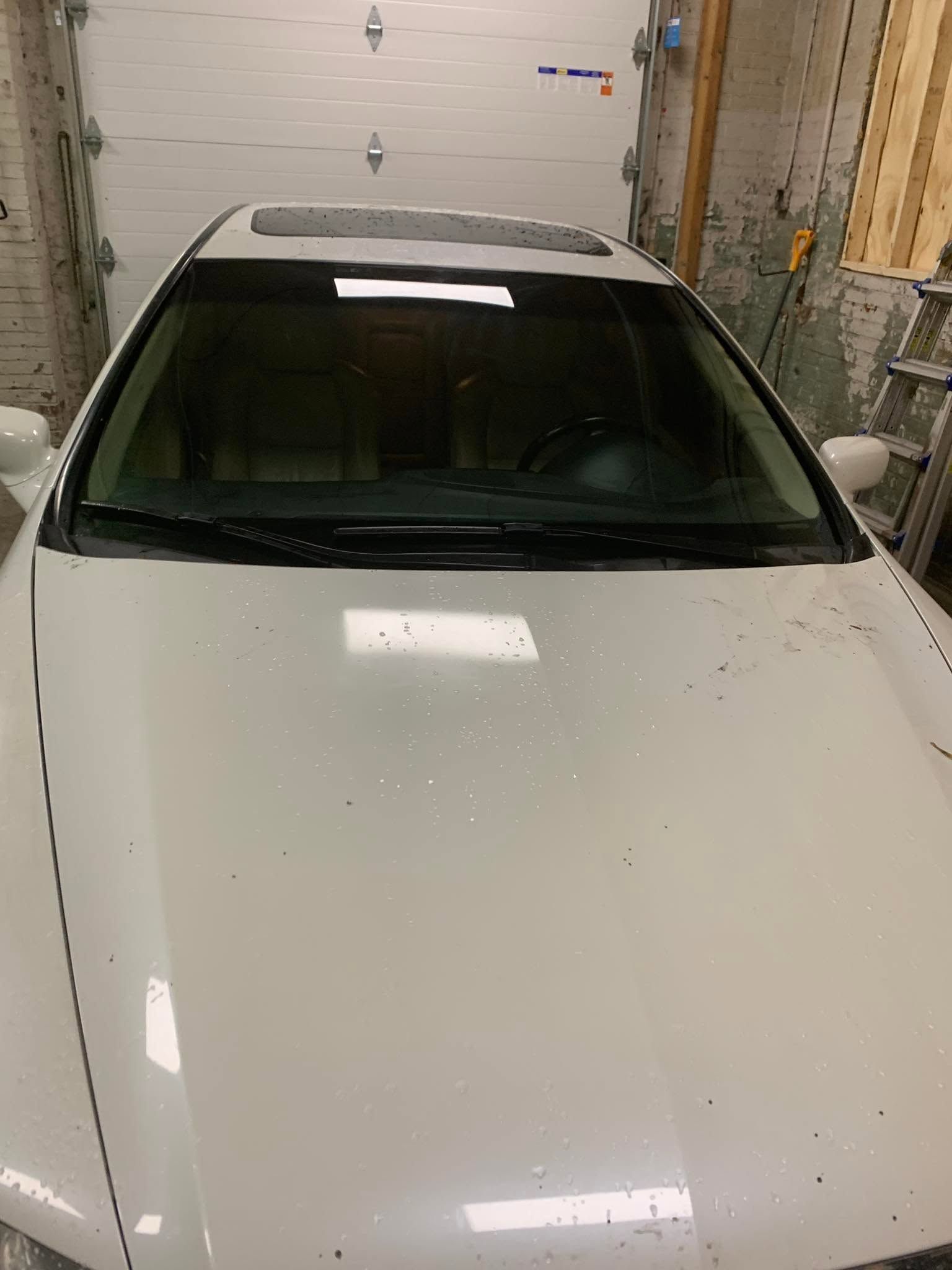 White car parked in a garage, viewed from above.