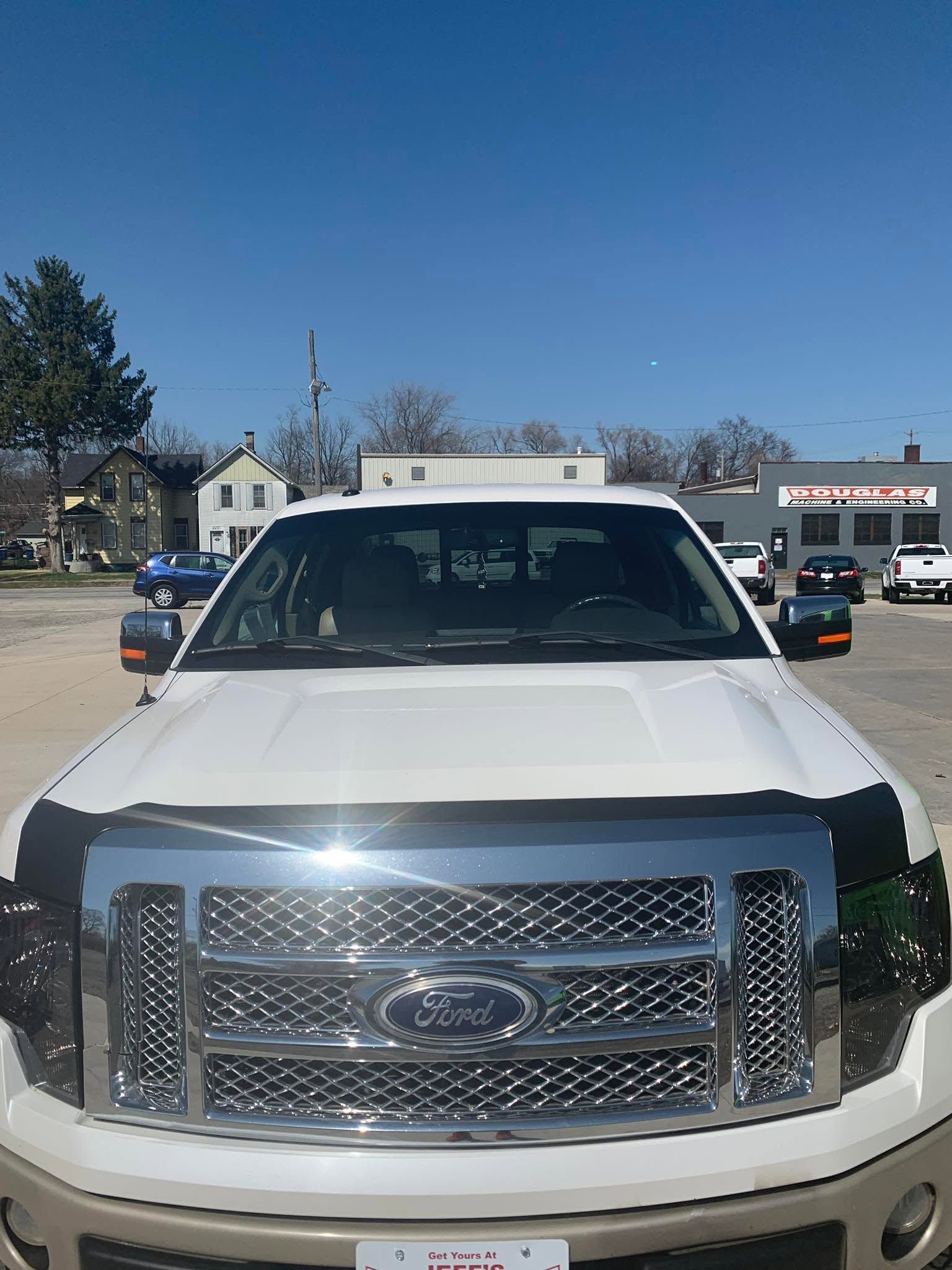 White Ford truck parked outdoors under a clear blue sky.