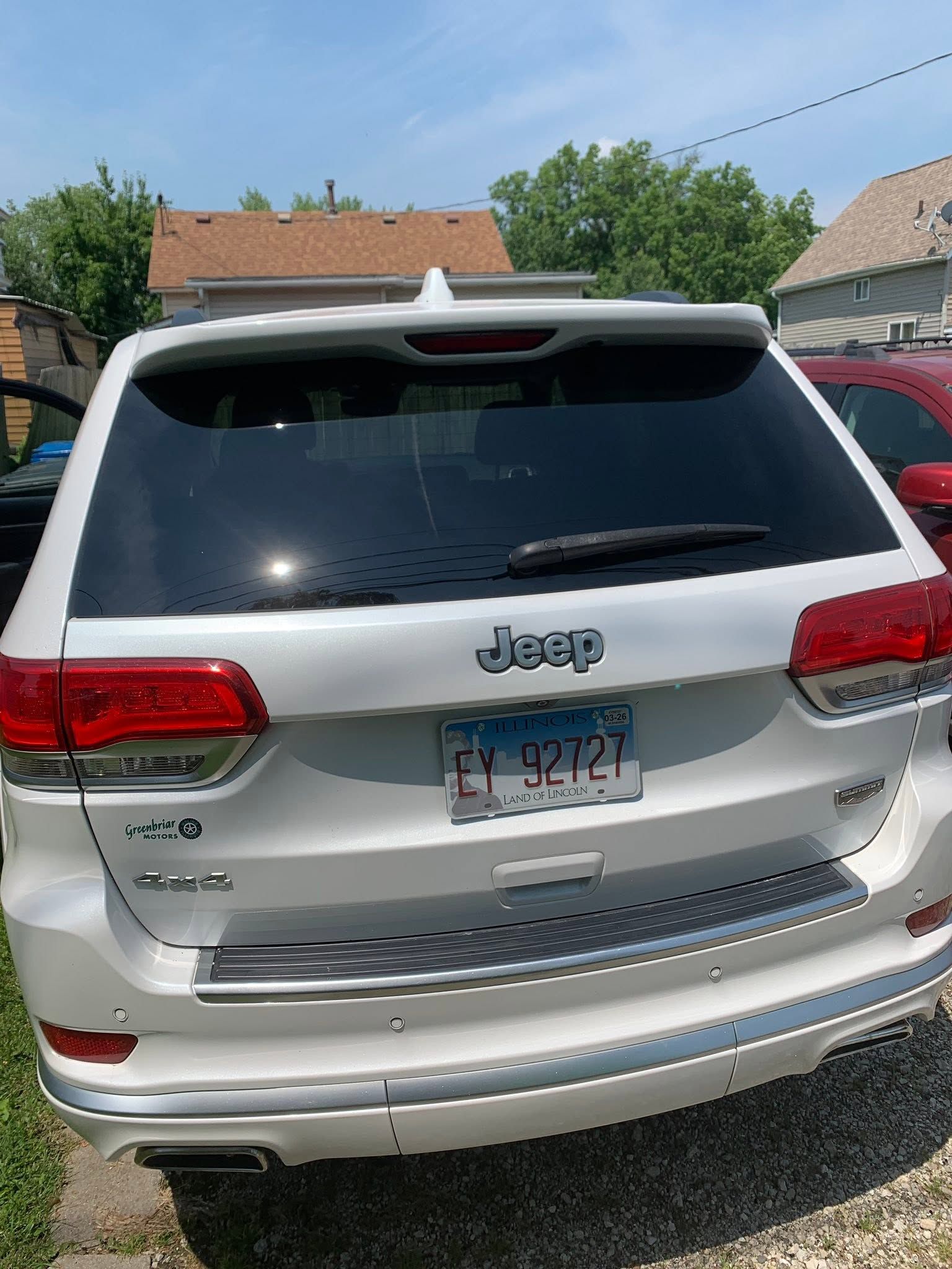 Rear view of a silver Jeep SUV parked outdoors with a license plate visible.